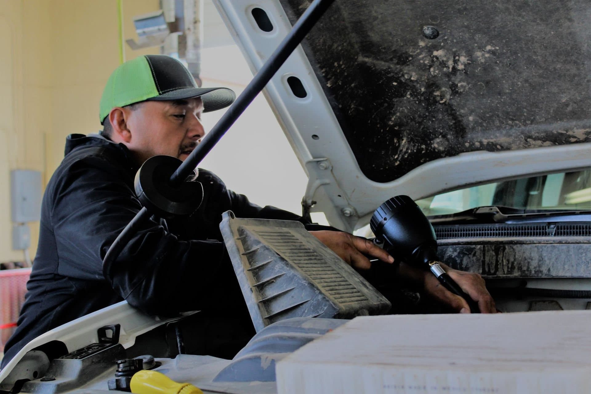 A Shine Brite technician working under the hood of a truck in a service bay